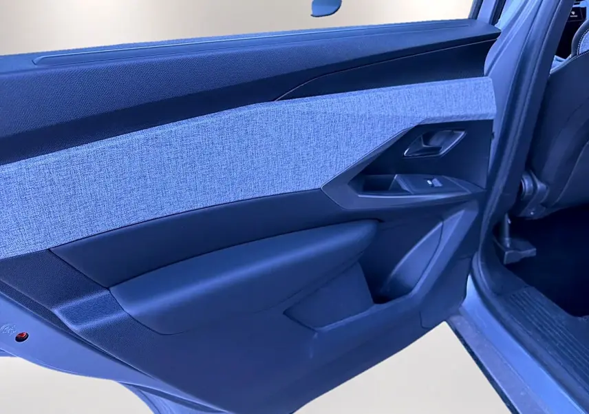 Vue rapprochée de la porte arrière gauche du Peugeot 5008 gris artense, avec insert tissu clair et commandes de vitre.