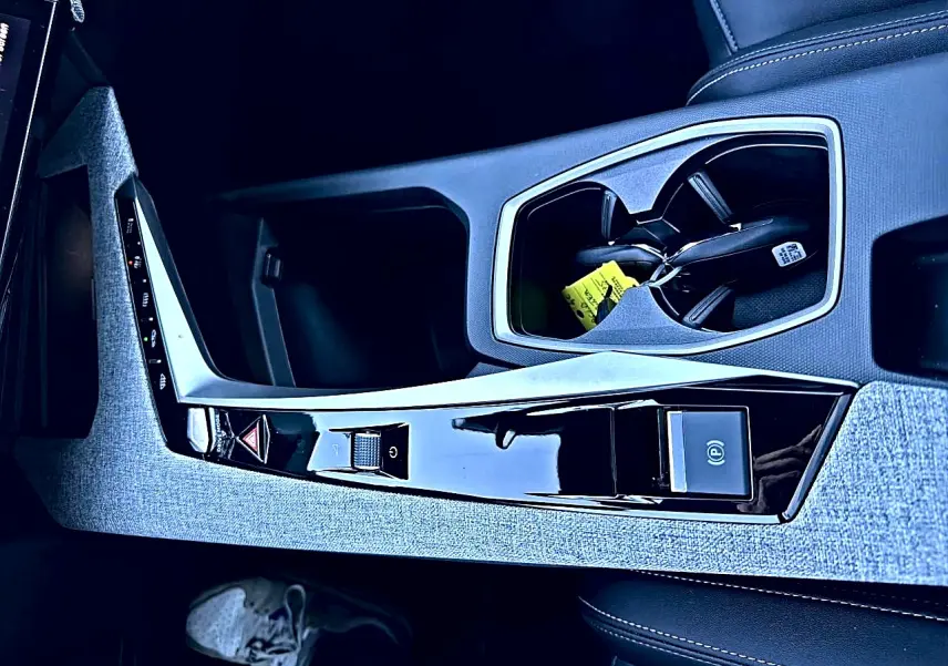 Vue rapprochée de la console centrale grise et noire du Peugeot 5008 Hybrid 145 allure e-dcs6 avec porte-gobelets et commandes tactiles.