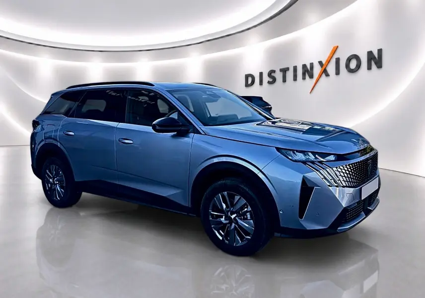 Peugeot 5008 Hybrid 145 allure e-dcs6 gris artense, vue 3/4 avant droit dans un showroom lumineux.