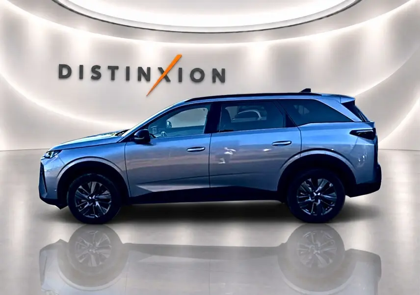 Profil droit du Peugeot 5008 Hybrid 145 allure e-dcs6 gris artense dans un showroom lumineux avec reflet au sol.