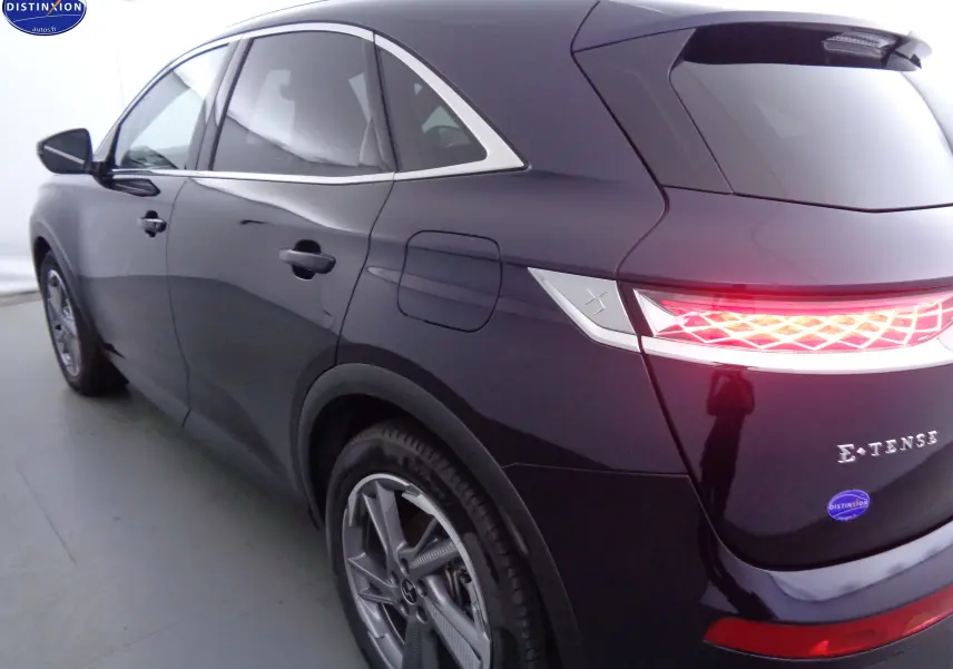 Vue 3/4 arrière droite d'un DS7 Crossback hybride rechargeable bleu encre métal avec feux arrière LED allumés.