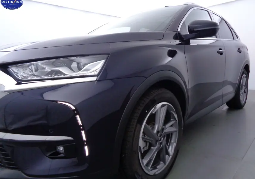 Vue 3/4 avant droit d'un DS7 Crossback hybride rechargeable bleu encre métal avec feux LED et jantes alliage.