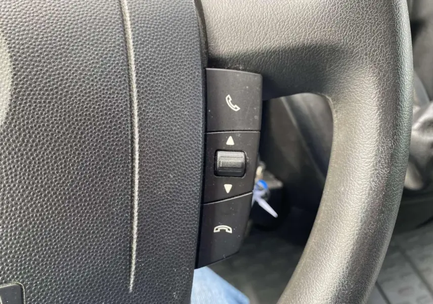 Gros plan sur les commandes téléphoniques au volant noir de l'Opel Movano Fourgon blanc, version 2022.