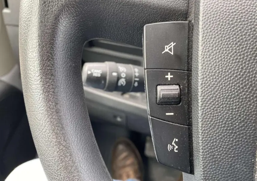 Gros plan sur les commandes de volume et de coupure sonore au volant d'un Opel Movano Fourgon blanc de 2022.