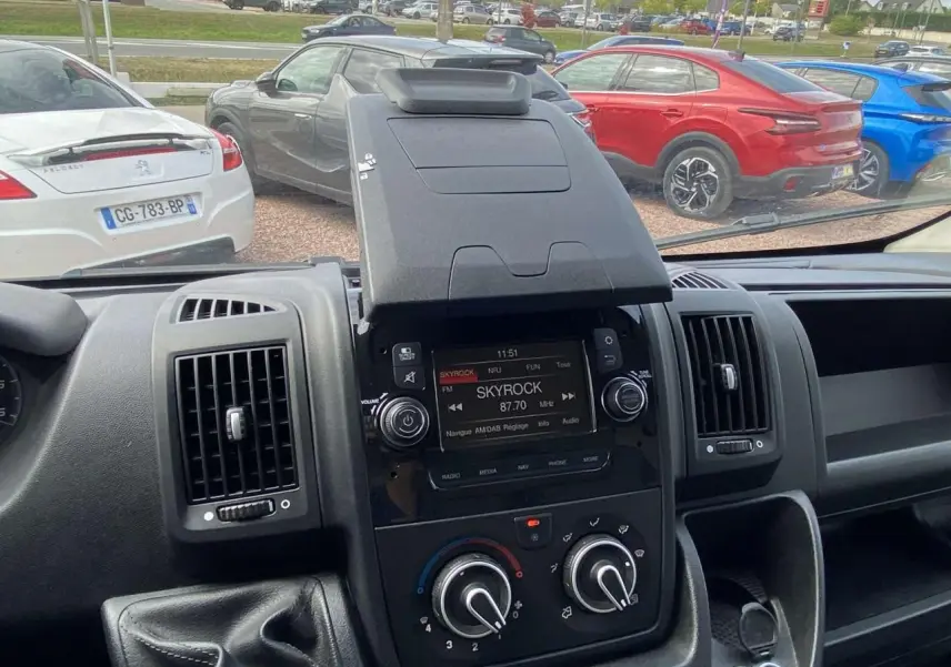 Vue intérieure du tableau de bord de l'Opel Movano Fourgon 2022 avec écran radio Skyrock et commandes de climatisation.