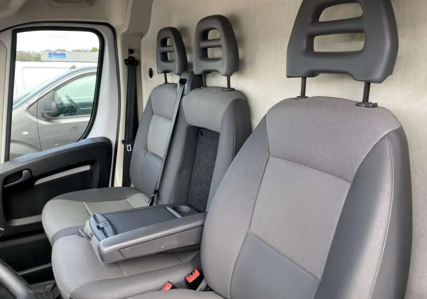 Intérieur du fourgon Opel Movano blanc 2022, vue côté gauche sur les sièges avant gris avec accoudoir conducteur.