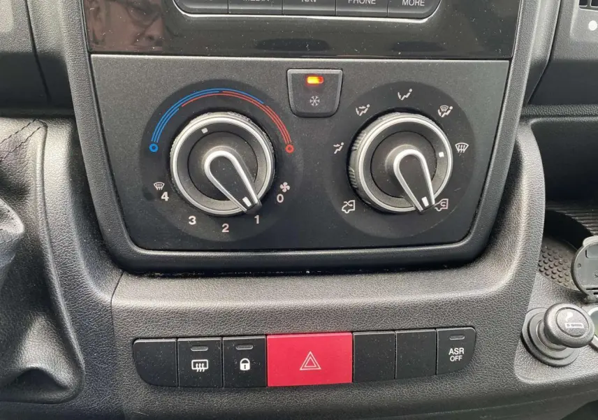 Gros plan sur les commandes de climatisation et les boutons de sécurité du tableau de bord du fourgon Opel Movano blanc.