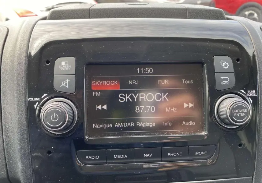 Écran central de la radio numérique du fourgon Opel Movano blanc, affichant la station Skyrock à 87,7 MHz.