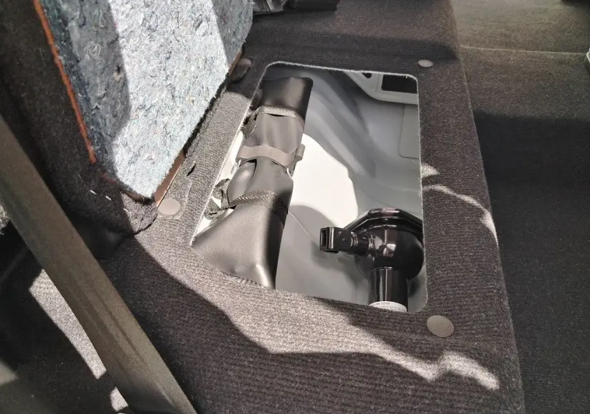 Détail du compartiment de rangement sous le siège arrière du pick-up Isuzu D-MAX blanc, montrant un crochet d'attelage.