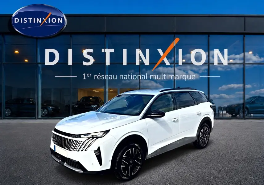 Peugeot 5008 blanc en 3/4 avant droit, avec jantes alu noires et toit noir, devant une vitrine Distinxion.