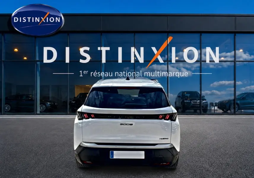 Vue arrière d’un Peugeot 5008 Hybrid blanc garé devant une vitrine avec logo Distinxion.