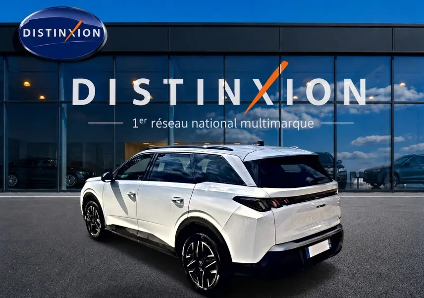 Peugeot 5008 blanc vue 3/4 arrière droit, jantes alu noires, vitres arrière surteintées, devant showroom Distinxion.