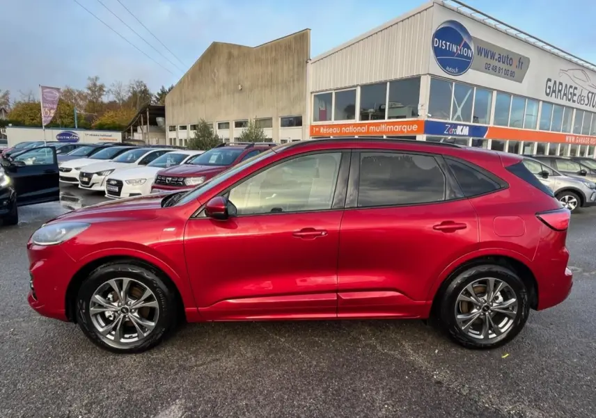 Vue de profil côté gauche d'un Ford Kuga 1.5 EcoBoost 150 ST-Line rouge Lucifer avec vitres surteintées.