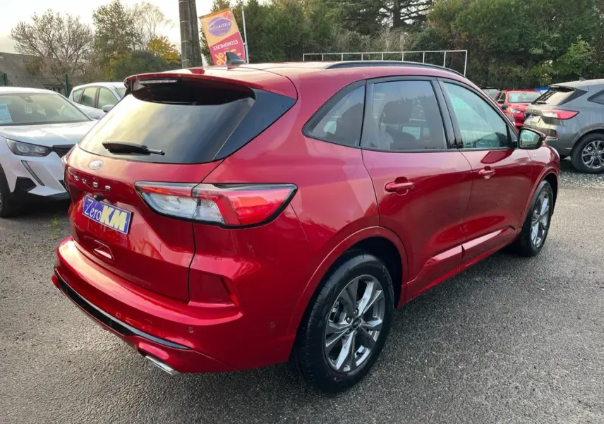 Vue 3/4 arrière droite du Ford Kuga ST-Line rouge Lucifer avec vitres surteintées et double sortie d'échappement.