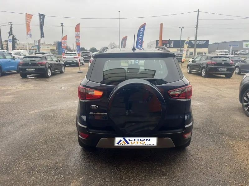 Vue arrière d'un Ford EcoSport Bleu Abysse avec roue de secours sur porte et barres de toit visibles.