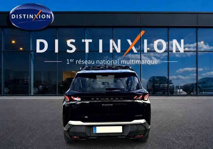 Vue arrière d'un Peugeot 5008 Hybrid 145 GT noir, avec feux arrière LED et becquet arrière visible devant une vitrine Distinxion.
