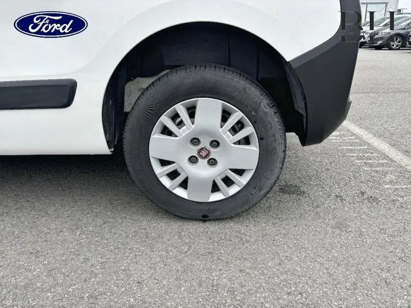 Gros plan sur la roue avant droite blanche d'un FIAT Fiorino 2018 avec enjoliveur et logo Fiat visible.