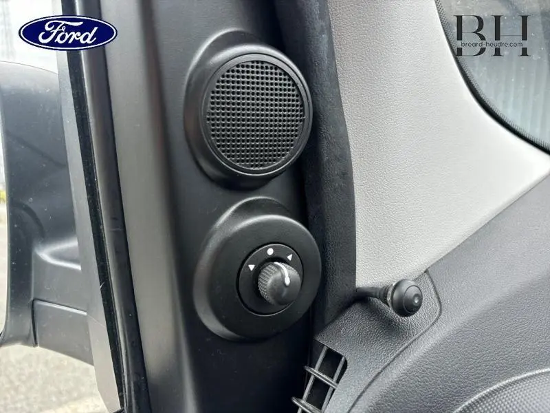 Gros plan sur le panneau de réglage des rétroviseurs et haut-parleur côté gauche intérieur d'un Fiat Fiorino blanc.