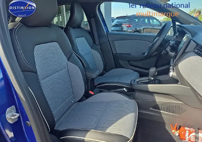 Vue intérieure avant droite de la Renault Clio V 1.6 e-tech 145 techno bleu iron avec sièges sport gris et noir.