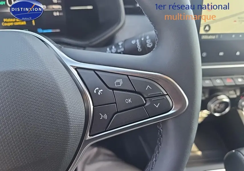 Gros plan sur les commandes multifonctions du volant noir de la Renault Clio V 1.6 e-tech 145 techno 2025.