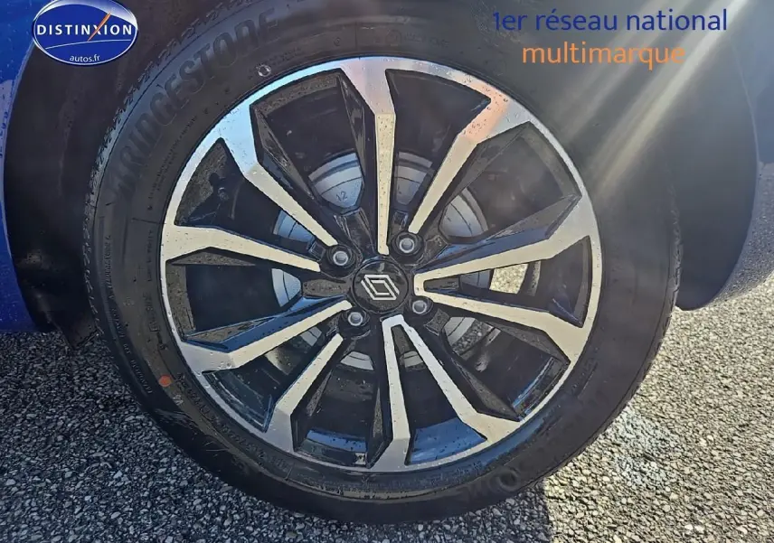 Gros plan sur la jante alu noire et argentée d'une Renault Clio V Bleu Iron, avec logo Renault au centre.