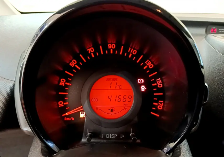 Vue rapprochée du compteur de vitesse rouge éclairé de la Citroën C1 blanche, affichant 41669 km et 11°C extérieur.