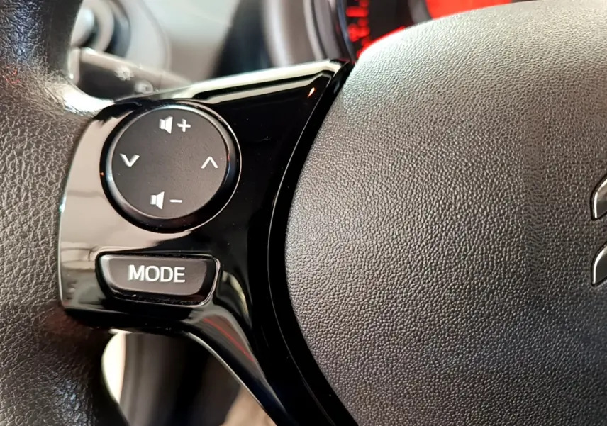 Gros plan sur les commandes audio noires intégrées au volant en cuir noir du Citroën C1 blanc, version 2020.