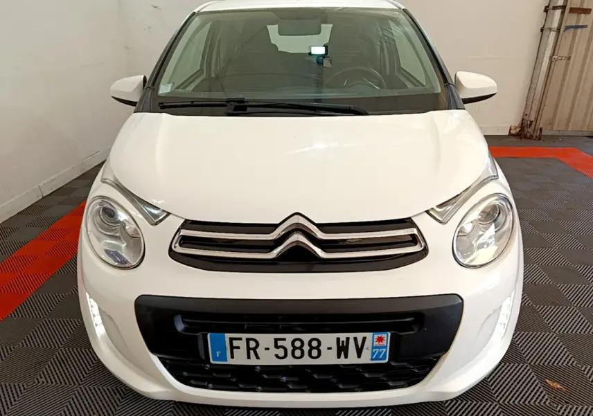 Vue avant d'une Citroën C1 blanche 2020 avec feux LED et calandre noire dans un garage.