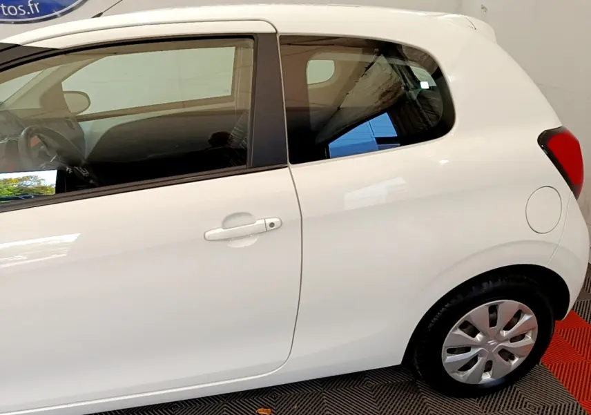 Vue latérale droite d'une Citroën C1 blanche de 2020, mettant en valeur la porte et la roue arrière.