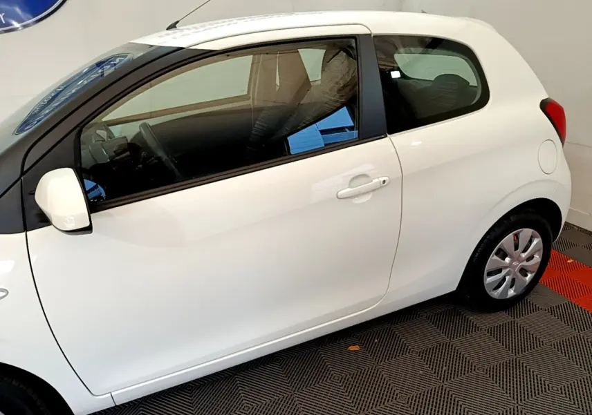 Vue de profil côté gauche d'une Citroën C1 blanche 3 portes, avec rétroviseur peint et jantes compactes.