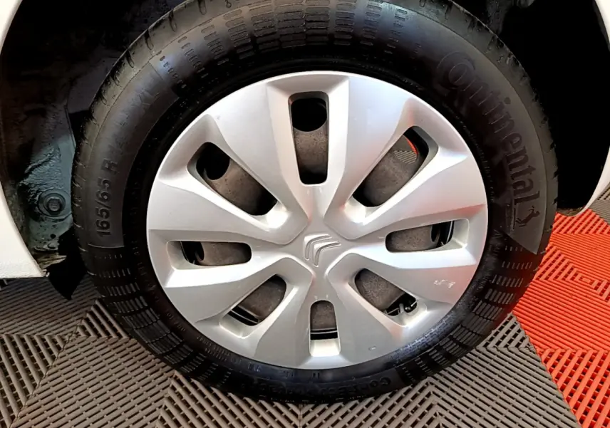 Gros plan sur la roue avant droite d'une Citroën C1 blanche avec enjoliveur argenté et pneu Continental.