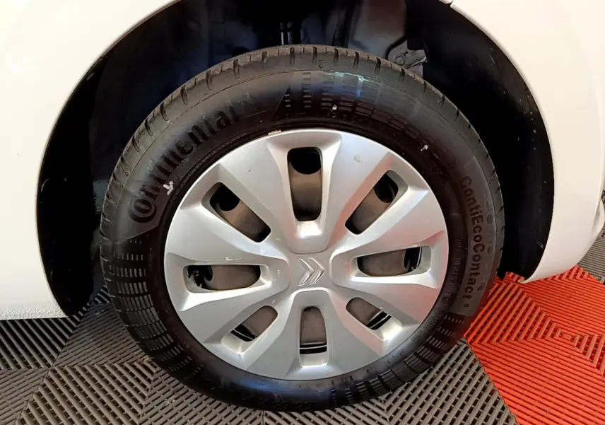 Gros plan sur la roue avant droite d'une Citroën C1 blanche de 2020 avec enjoliveur argenté et pneu Continental.
