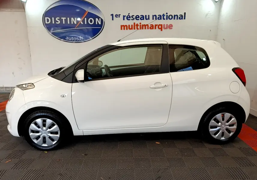 Profil côté gauche d'une Citroën C1 blanche 3 portes de 2020, compacte et épurée en intérieur showroom.