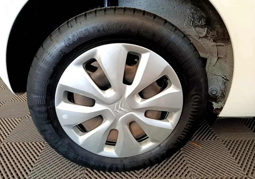 Gros plan sur la roue avant droite d'une Citroën C1 blanche avec enjoliveur argenté et logo Citroën central.