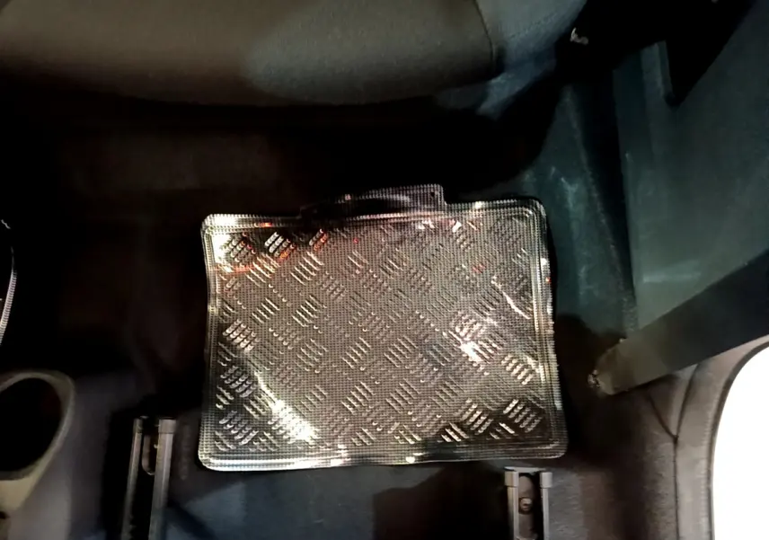 Gros plan sur le tapis de sol noir à motif damier dans l'habitacle d'une Citroën C1 blanche, côté passager arrière.