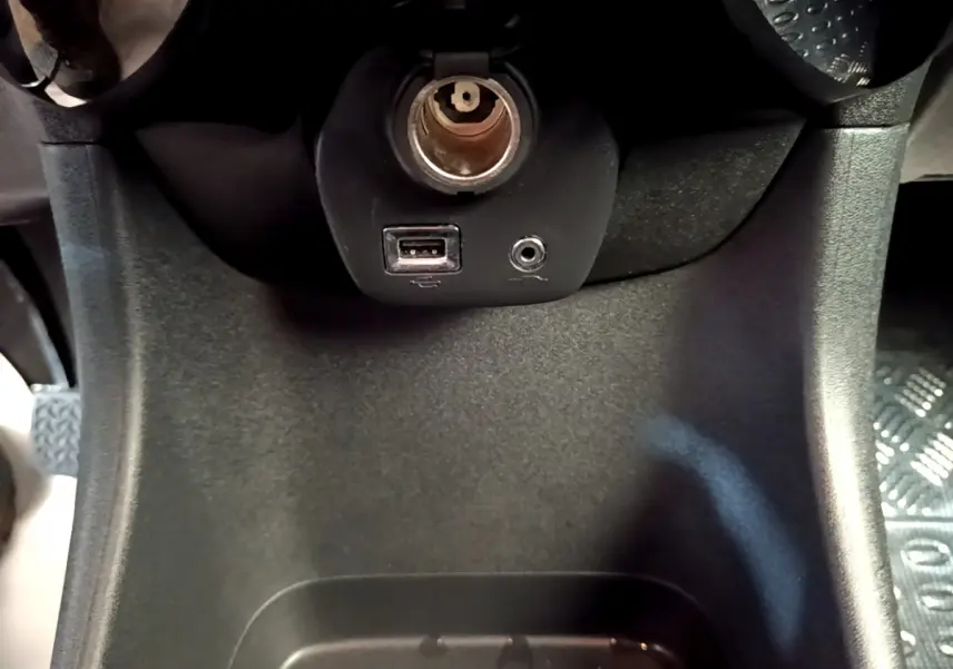 Vue rapprochée de la prise 12V, port USB et entrée audio dans l’habitacle de la Citroën C1 blanche de 2020.