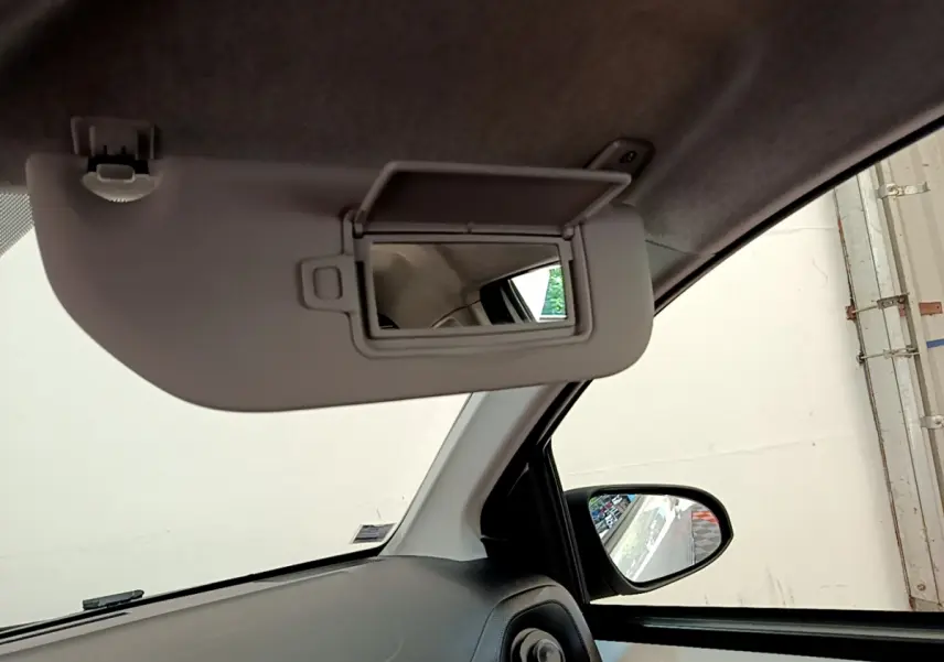 Détail intérieur du pare-soleil avec miroir ouvert côté conducteur d'une Citroën C1 blanche, vue vers la portière.
