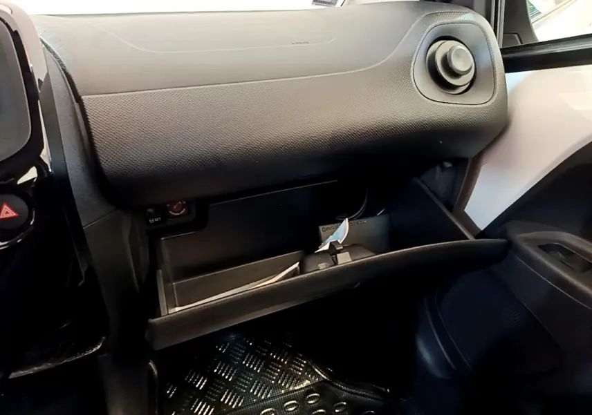 Vue intérieure côté passager du coffre à gants ouvert dans une Citroën C1 blanche, tableau de bord noir texturé visible.