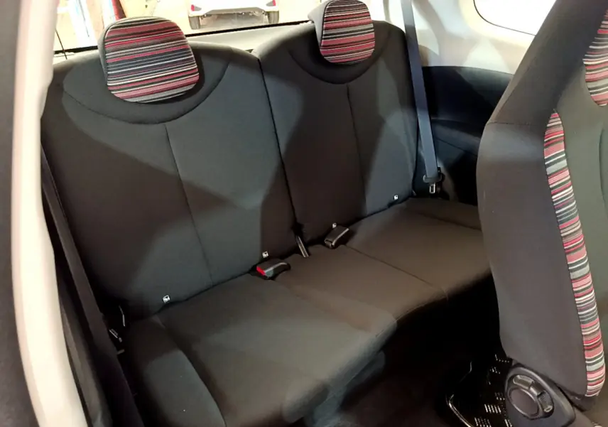 Vue intérieure arrière de la banquette noire avec appuie-têtes rayés rouge et gris de la Citroën C1 blanche.