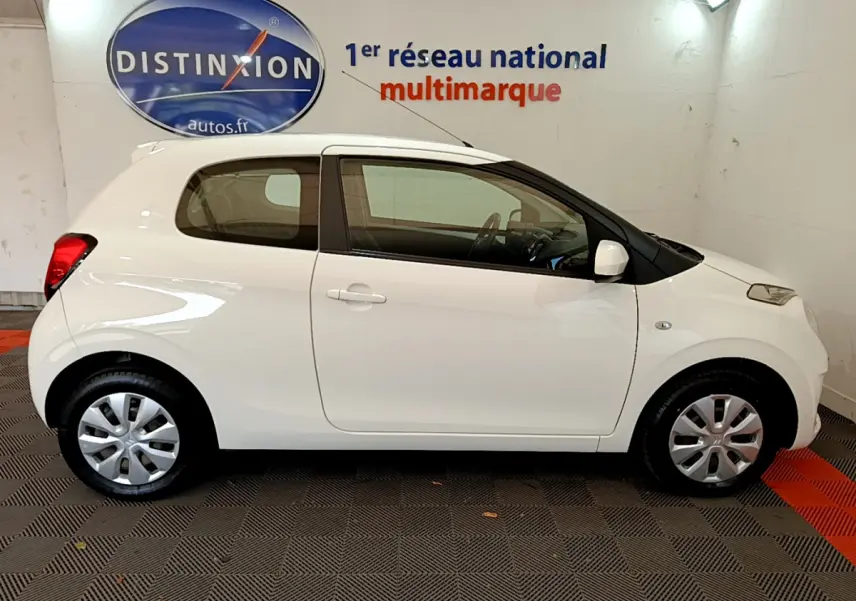 Profil côté droit d'une Citroën C1 blanche de 2020, compacte et épurée, dans un showroom intérieur.