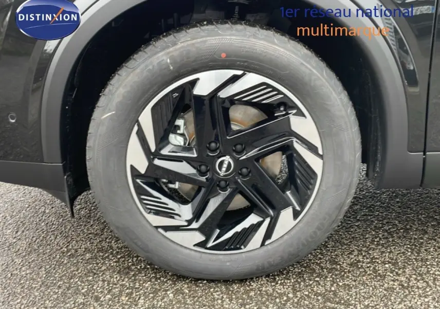 Gros plan sur la roue avant gauche noire perle métal du Nissan Qashqai 1.5 E-POWER avec jante alliage bicolore.