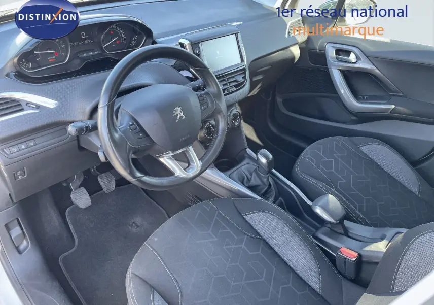 Vue intérieure côté conducteur du Peugeot 2008 blanc 2017, avec tableau de bord et sièges en tissu gris noir.