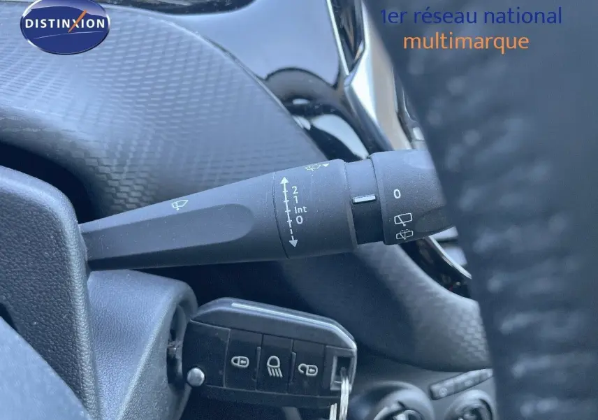 Gros plan sur la commande d'essuie-glace et la clé insérée dans le contact d'un Peugeot 2008 blanc, intérieur sombre.