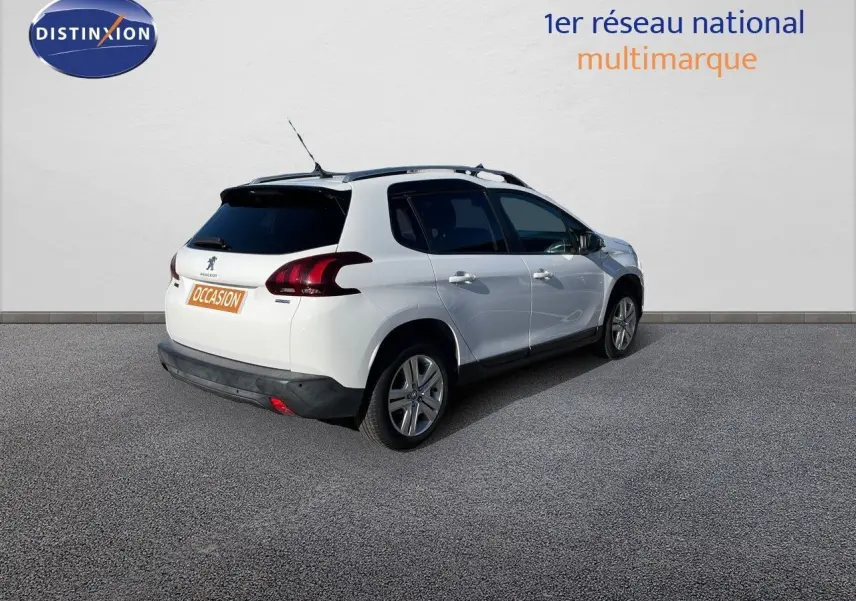 Peugeot 2008 blanc en 3/4 arrière droit, avec toit noir et feux arrière LED, stationné devant un mur blanc.