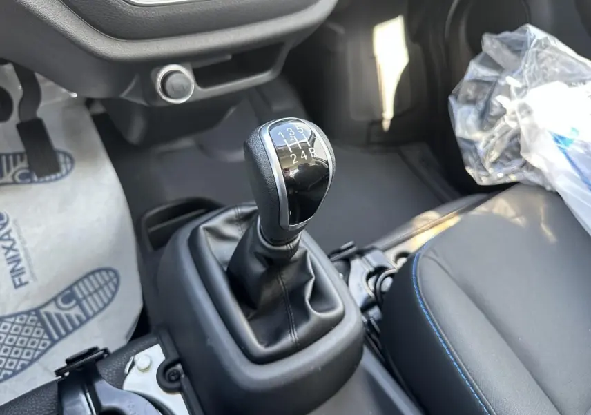 Le levier de vitesses manuel noir du Piaggio Porter 2024, vu en gros plan côté conducteur avec siège gris.