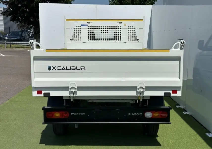 Vue arrière d'un Piaggio Porter blanc avec benne longue et marquage Xcalibur sur fond extérieur clair.