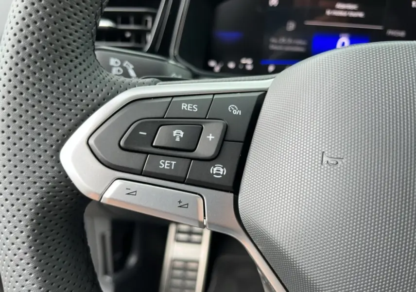Gros plan sur les commandes à gauche du volant perforé gris du Volkswagen T-Roc TDI 150 DSG7 R-Line Black 2025.