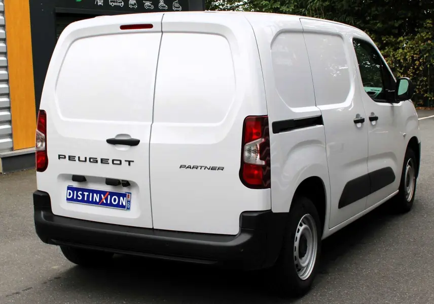 Vue 3/4 arrière droite d’un Peugeot Partner Fourgon blanc 2025 avec portes arrière battantes et protections noires.