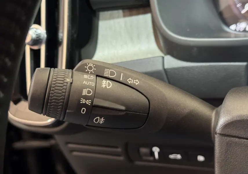 Gros plan sur la commande des phares et clignotants à gauche du volant dans l’habitacle noir du Volvo XC40 Recharge T5 2021.