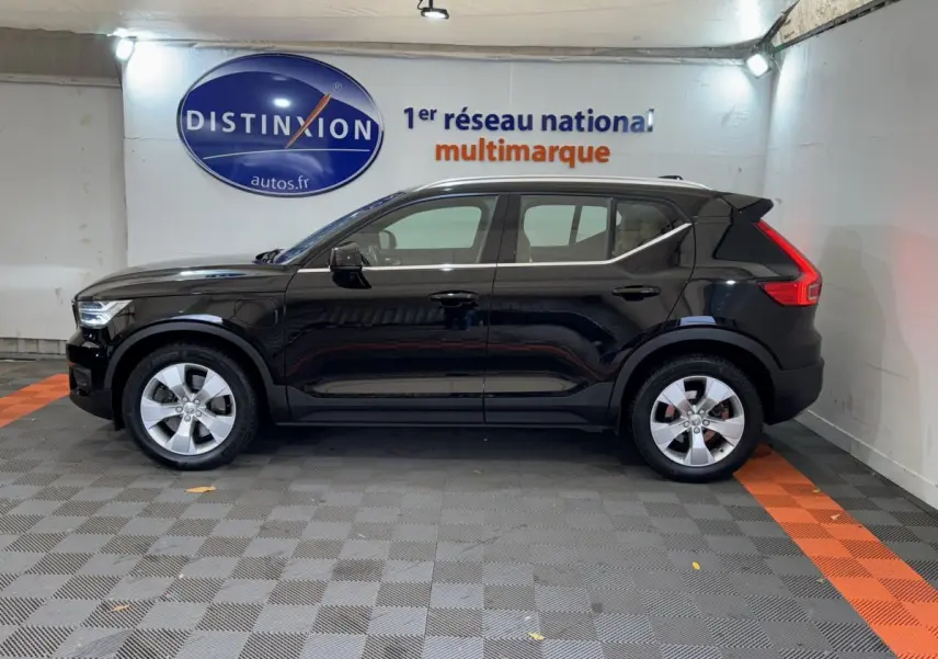 Profil côté gauche d'un Volvo XC40 Recharge T5 noir, hybride rechargeable, avec jantes argentées dans un garage.